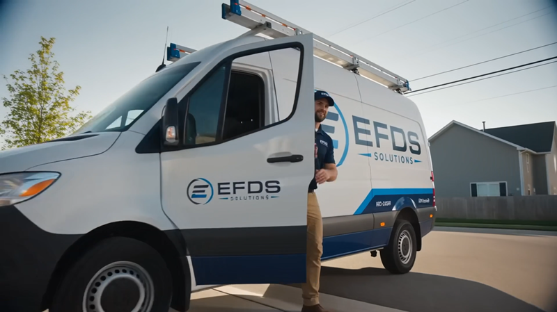 Illustrative commercial scene of a person beside an EFDS-branded service van